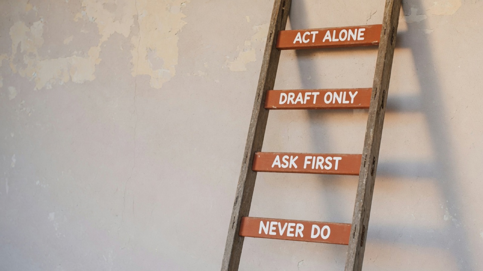 A wooden ladder against a plaster wall, its four rungs labelled from the bottom up — never do, ask first, draft only, act alone.
